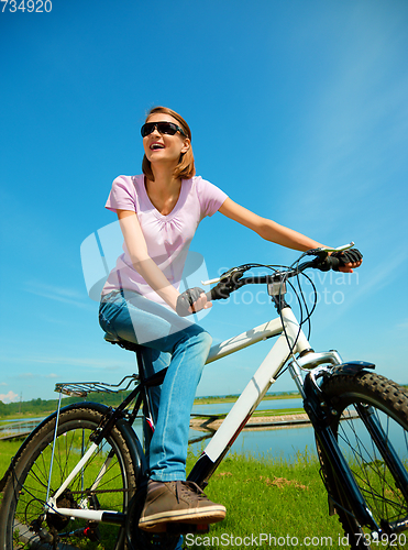 Image of Young woman is sitting on her bicycle