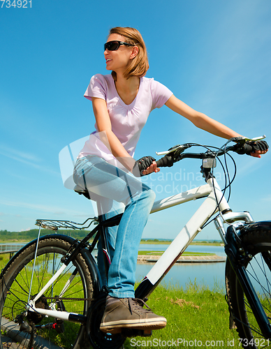 Image of Young woman is sitting on her bicycle