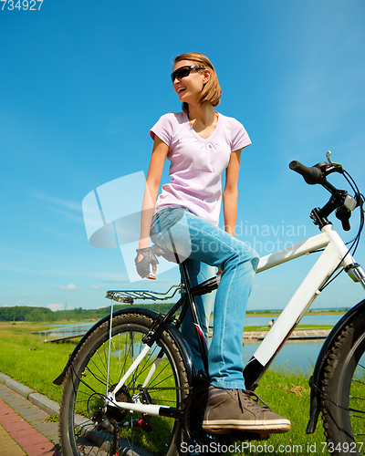 Image of Young woman is sitting on her bicycle