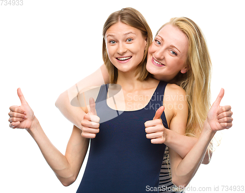 Image of Two young happy women showing thumb up sign