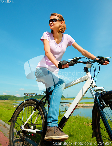 Image of Young woman is sitting on her bicycle