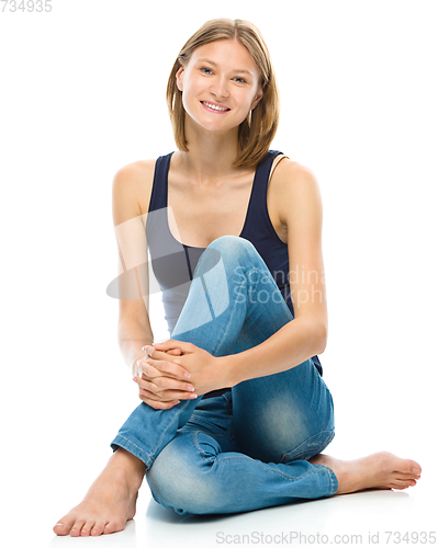 Image of Young happy woman is sitting on the floor