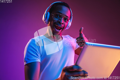 Image of Young african-american man\'s listening to music in neon light