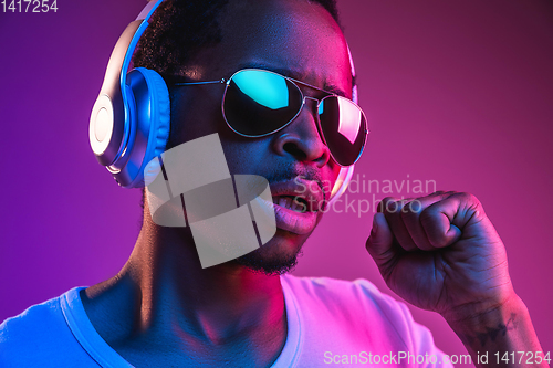 Image of Young african-american man\'s listening to music in neon light