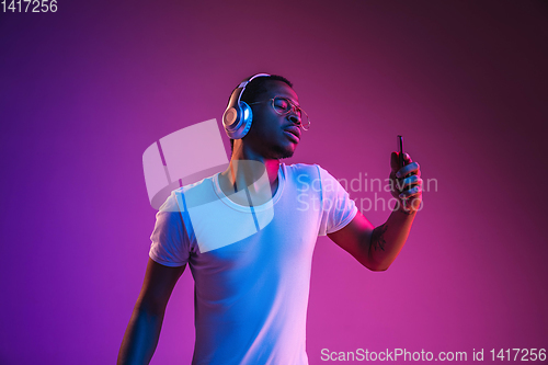 Image of Young african-american man\'s listening to music in neon light