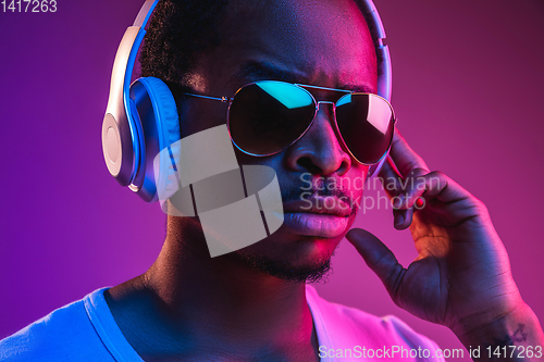 Image of Young african-american man\'s listening to music in neon light