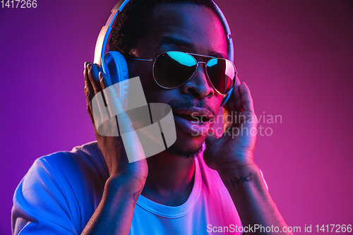 Image of Young african-american man\'s listening to music in neon light