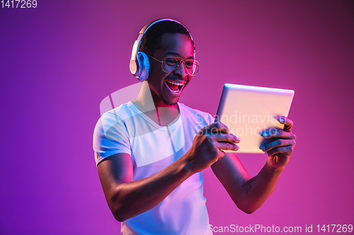 Image of Young african-american man\'s listening to music in neon light