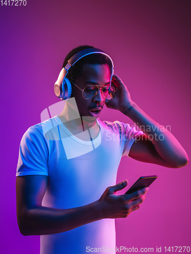 Image of Young african-american man\'s listening to music in neon light