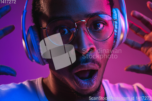 Image of Young african-american man\'s listening to music in neon light