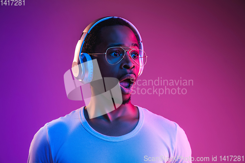 Image of Young african-american man\'s listening to music in neon light