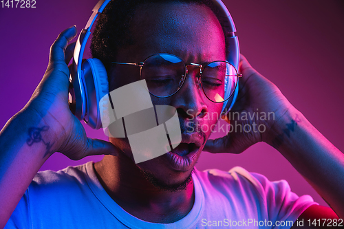 Image of Young african-american man\'s listening to music in neon light