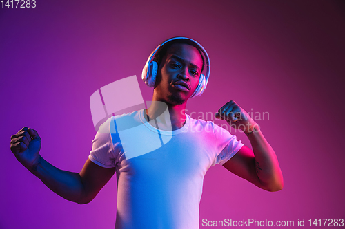 Image of Young african-american man\'s listening to music in neon light