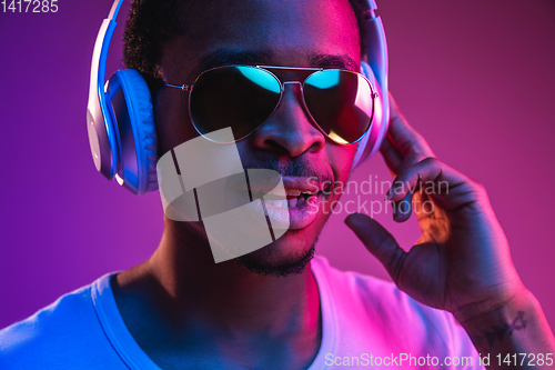 Image of Young african-american man\'s listening to music in neon light