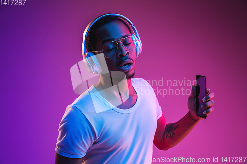 Image of Young african-american man\'s listening to music in neon light