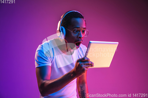 Image of Young african-american man\'s listening to music in neon light