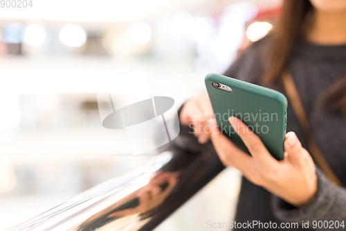 Image of Woman sending sms on mobile phone in shopping mall