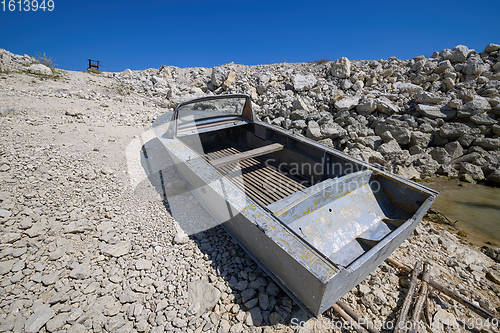 Image of Empty old metal fishing motor boat at shore