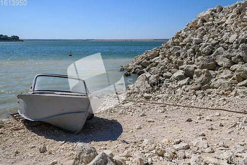 Image of Empty old metal fishing motor boat at shore.