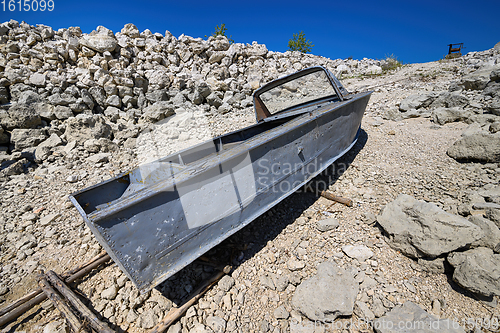 Image of Empty old metal fishing motor boat at shore