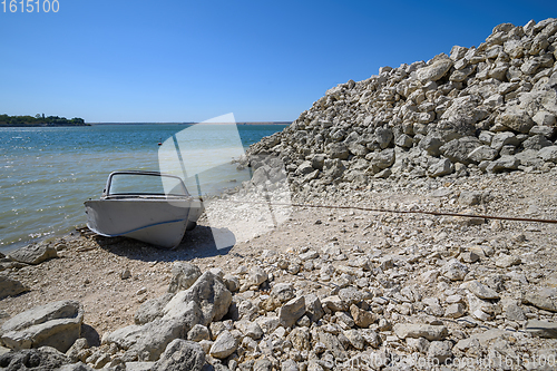 Image of Empty old metal fishing motor boat at shore