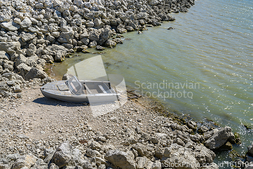 Image of Empty old metal fishing motor boat at shore