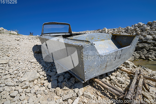 Image of Empty old metal fishing motor boat at shore