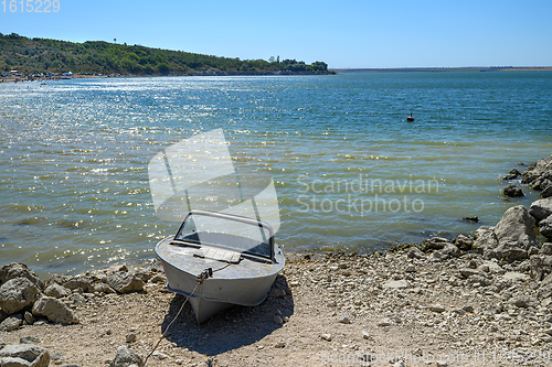 Image of Empty old metal fishing motor boat at shore