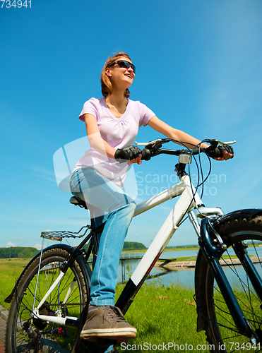 Image of Young woman is sitting on her bicycle