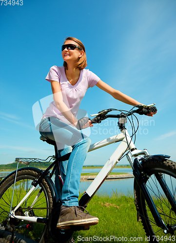Image of Young woman is sitting on her bicycle