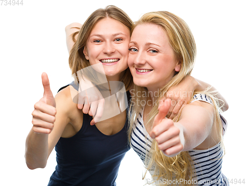 Image of Two young happy women showing thumb up sign