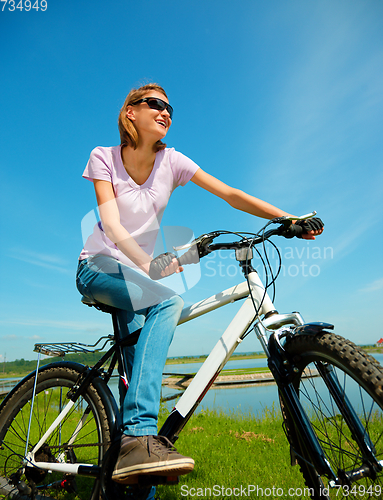 Image of Young woman is sitting on her bicycle