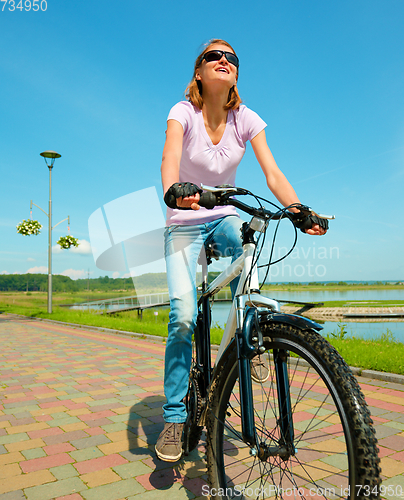 Image of Young woman is sitting on her bicycle