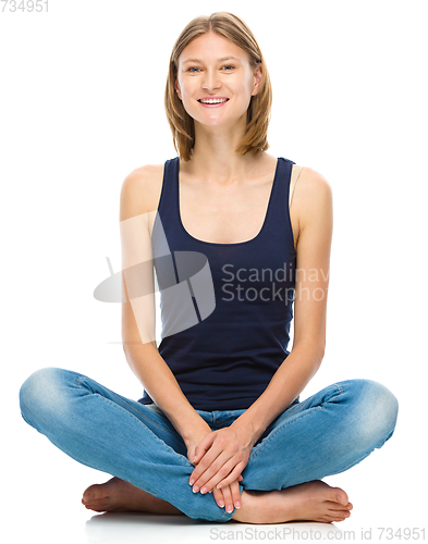 Image of Young happy woman is sitting on the floor