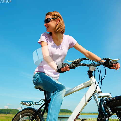 Image of Young woman is sitting on her bicycle