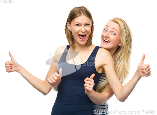 Image of Two young happy women showing thumb up sign
