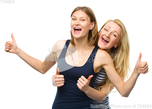 Image of Two young happy women showing thumb up sign