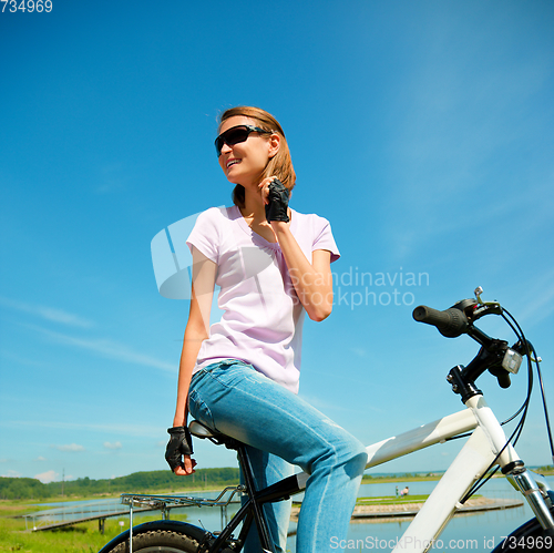 Image of Young woman is sitting on her bicycle