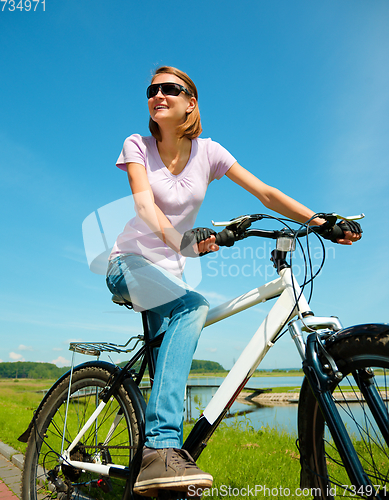 Image of Young woman is sitting on her bicycle