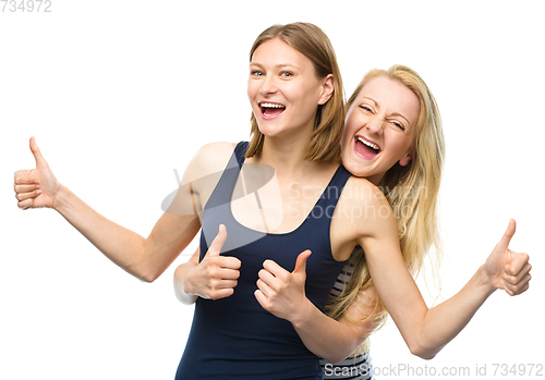 Image of Two young happy women showing thumb up sign