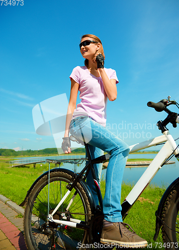 Image of Young woman is sitting on her bicycle
