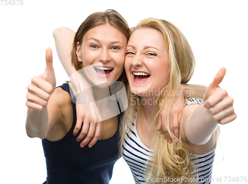 Image of Two young happy women showing thumb up sign