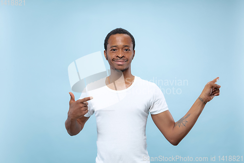 Image of Half-length close up portrait of young man on blue background.