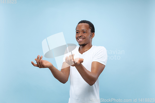 Image of Half-length close up portrait of young man on blue background.