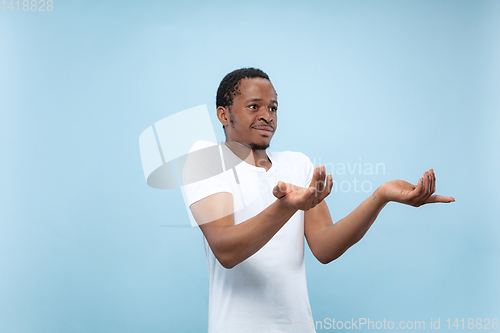 Image of Half-length close up portrait of young man on blue background.