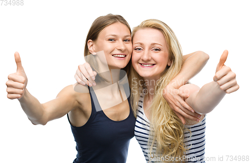Image of Two young happy women showing thumb up sign