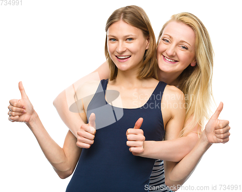 Image of Two young happy women showing thumb up sign