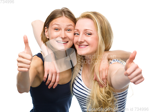 Image of Two young happy women showing thumb up sign
