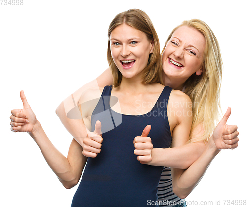 Image of Two young happy women showing thumb up sign