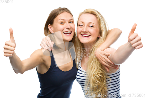 Image of Two young happy women showing thumb up sign